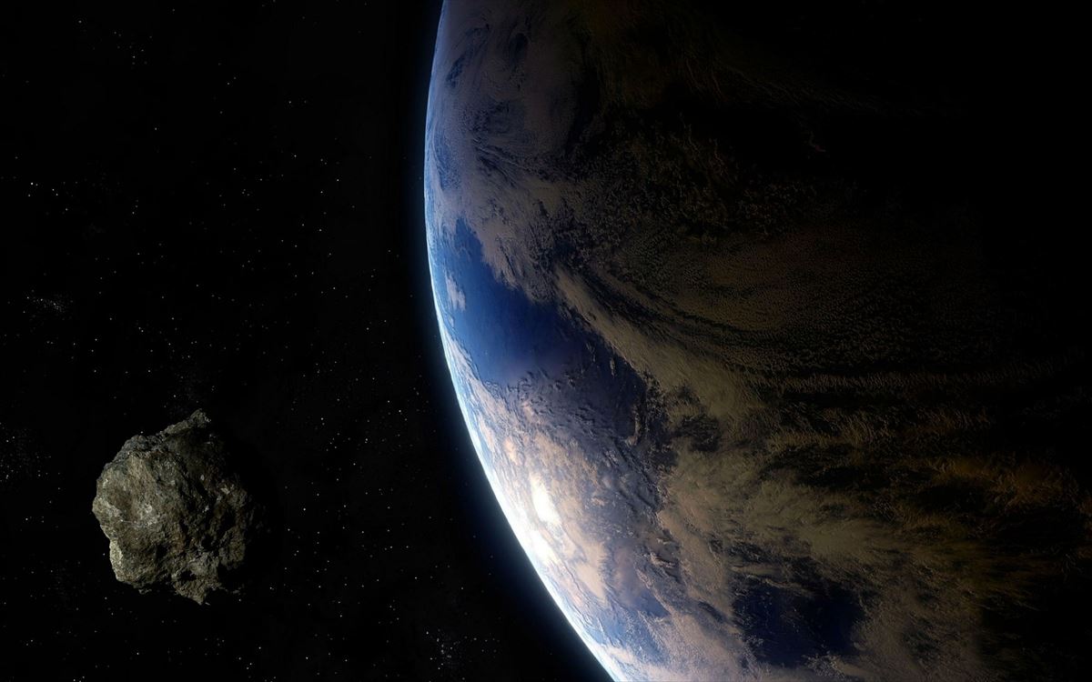 Un asteroide con la Tierra de fondo