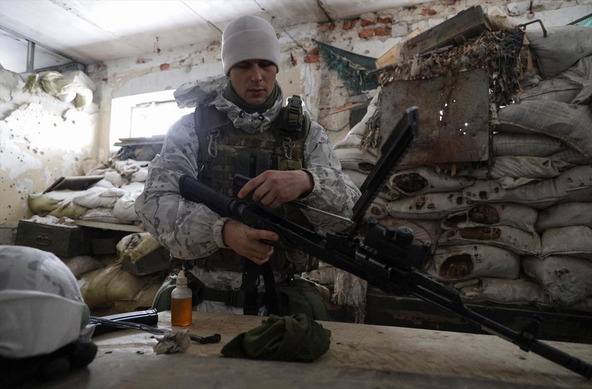 Ukrainako soldadu bat bere arma garbitzen, Errusiarekiko muga ondoan. Argazkia: EFE.