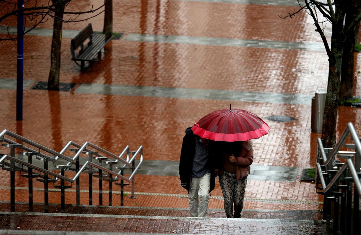 Dos personas se resguardan de la lluvia con un paraguas. 