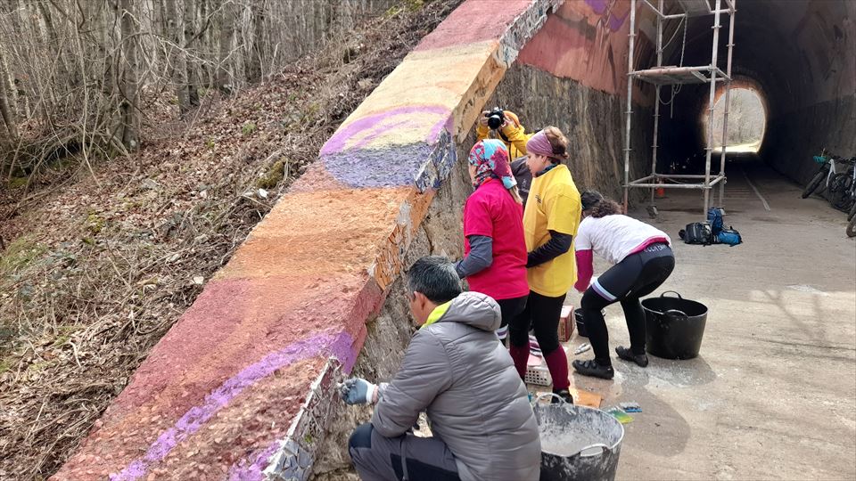 Cascan los azulejos para completar el mosaico cerámico de colores y los colocan uno a uno en el remate del túnel