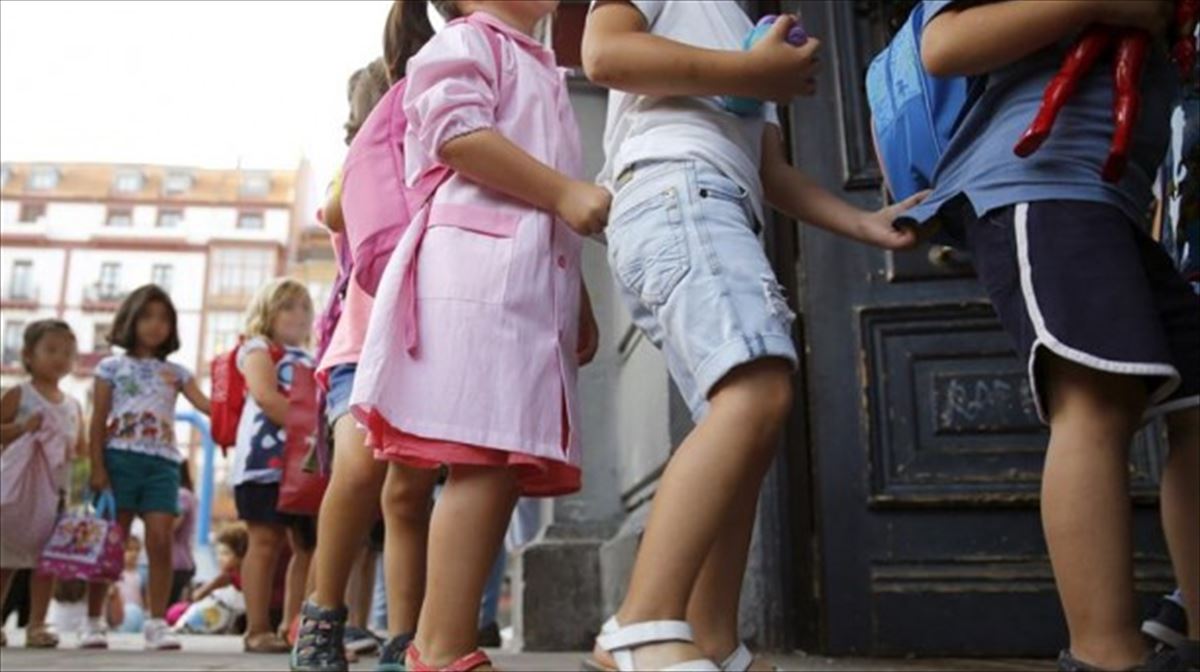 Varias niñas y niños a la entrada de un colegio. 