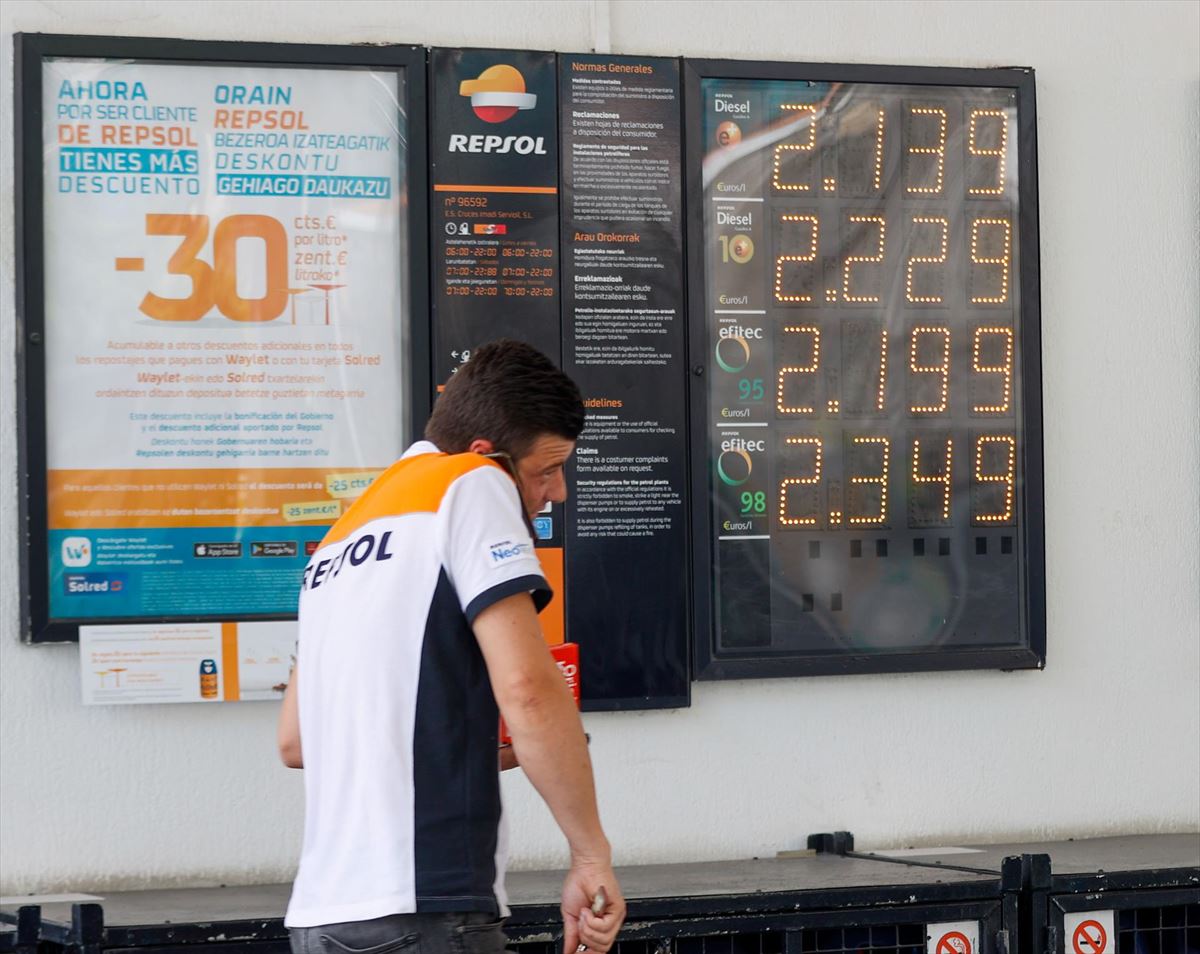 Un empleado de un surtidor pasa con los nuevos precios en una gasolinera de Bilbao. Foto: EFE