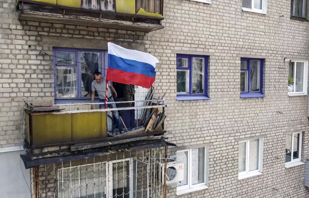 Un hombre instala la bandera rusa en el balcón, en Lugansk. EFE