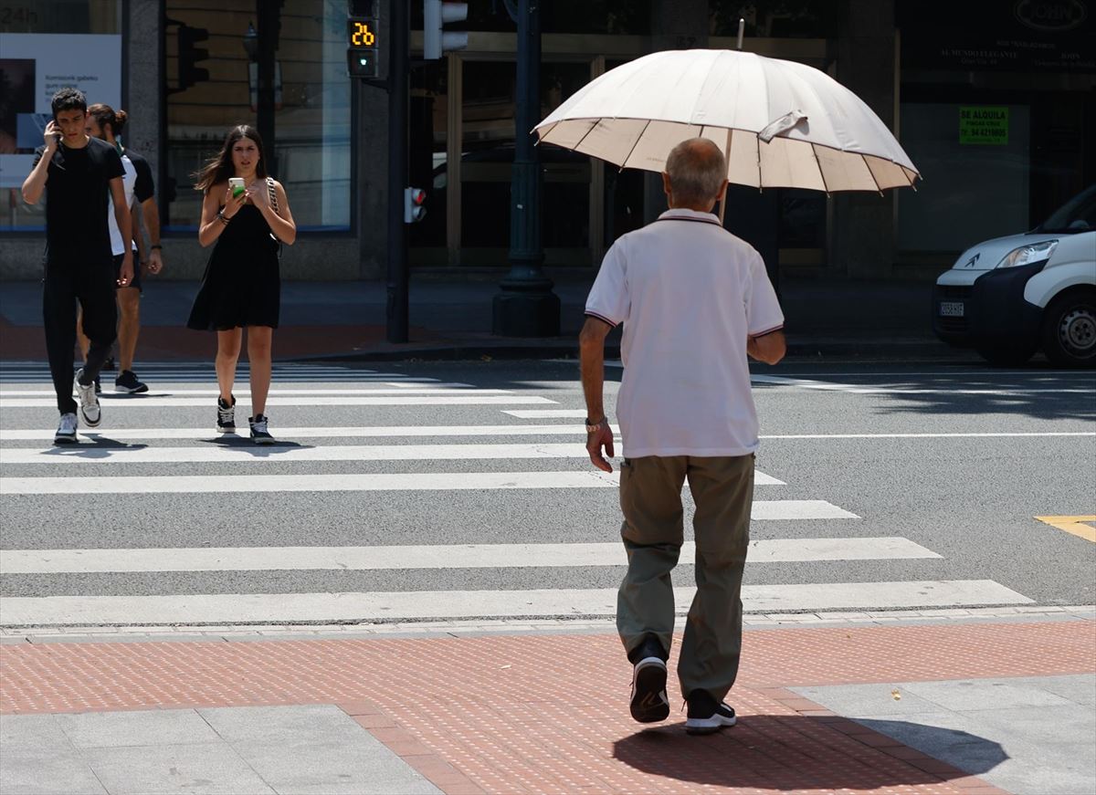 Un hombre se protege del calor con un paraguas. 