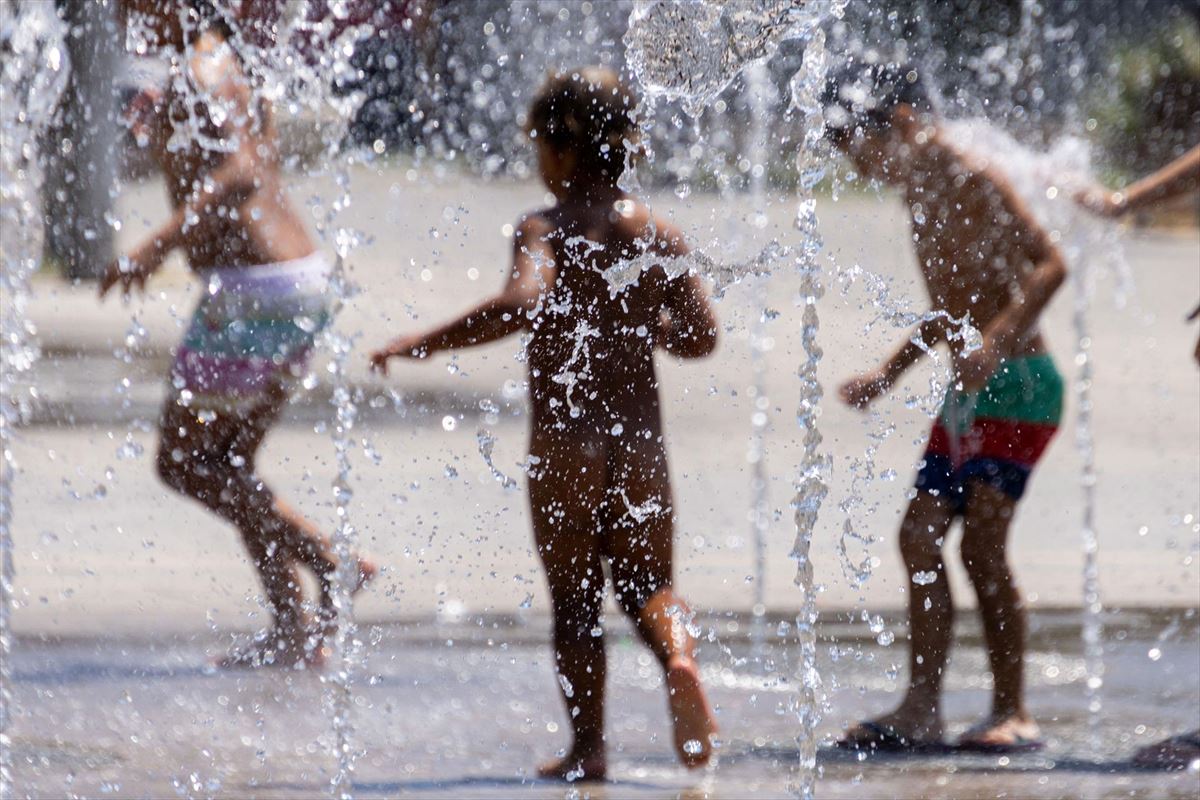 Varios niños juegan en unos chorros de agua este verano