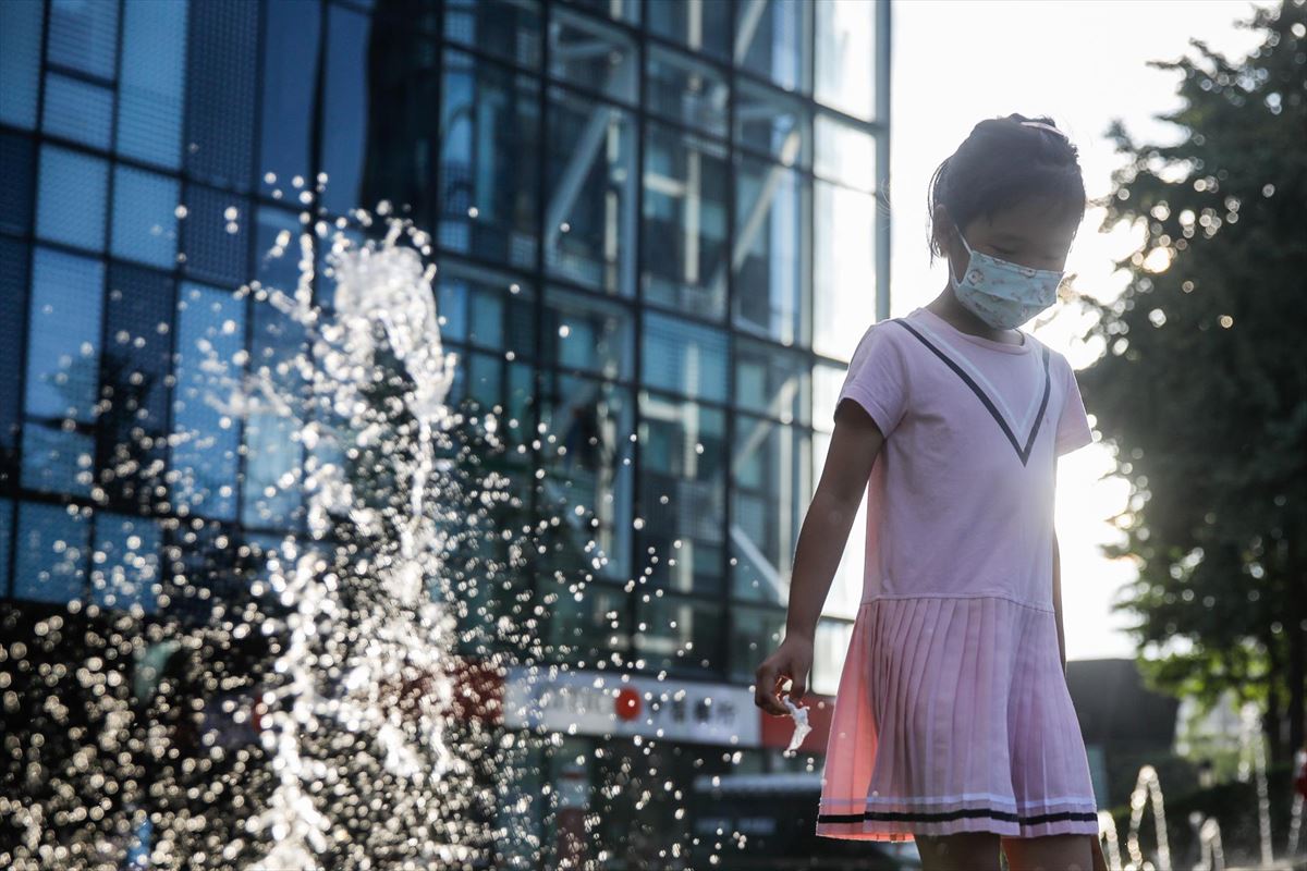 Una menor pasea por una calle de Pekín, la capital de China, con mascarilla
