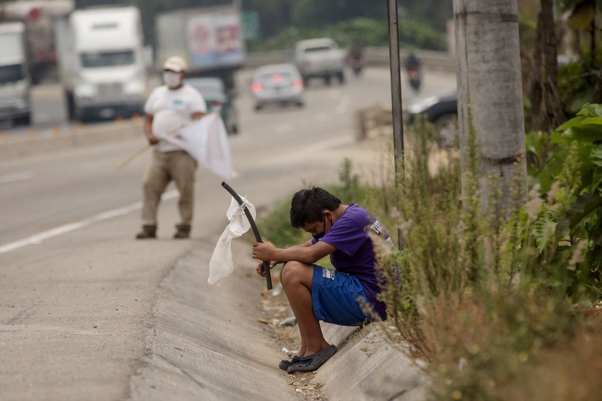Un niño ondea una bandera blanca en la carretera pidiendo ayuda por hambre, en Guatemala. Foto: EFE