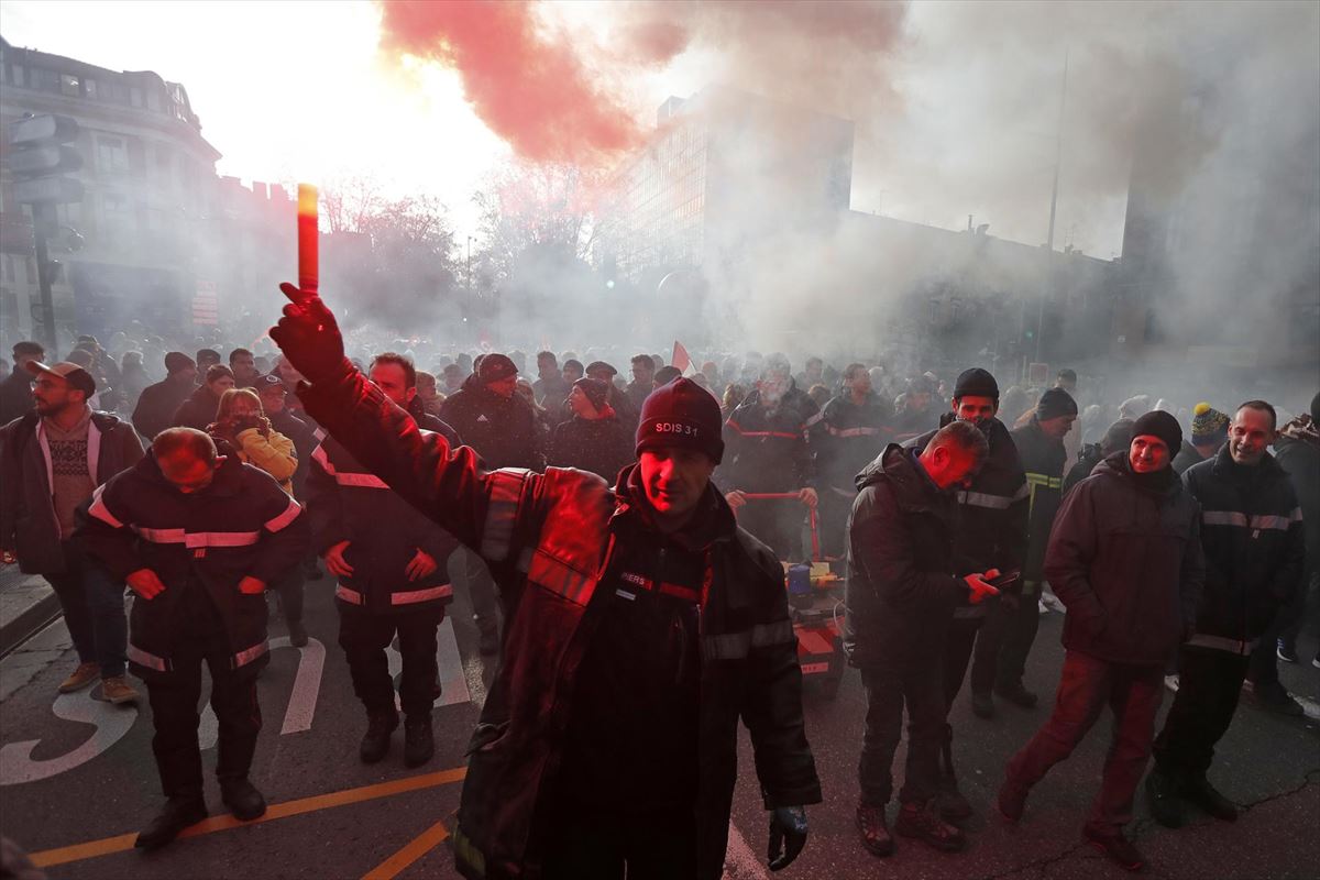 Un bombero enciende una bengala roja durante una huelga en Toulouse. Foto: EFE