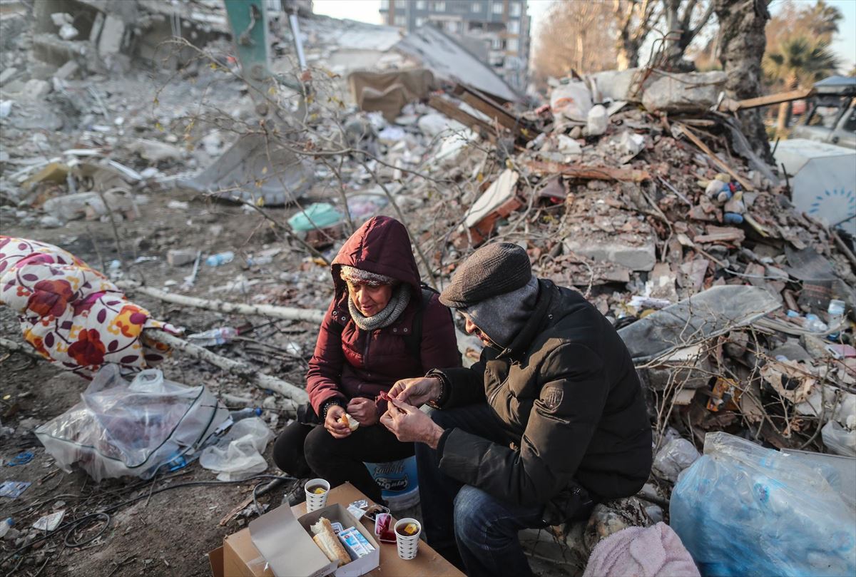 Dos supervivientes comparten comida sobre los escombros del terremoto en Turquía. Foto: EFE