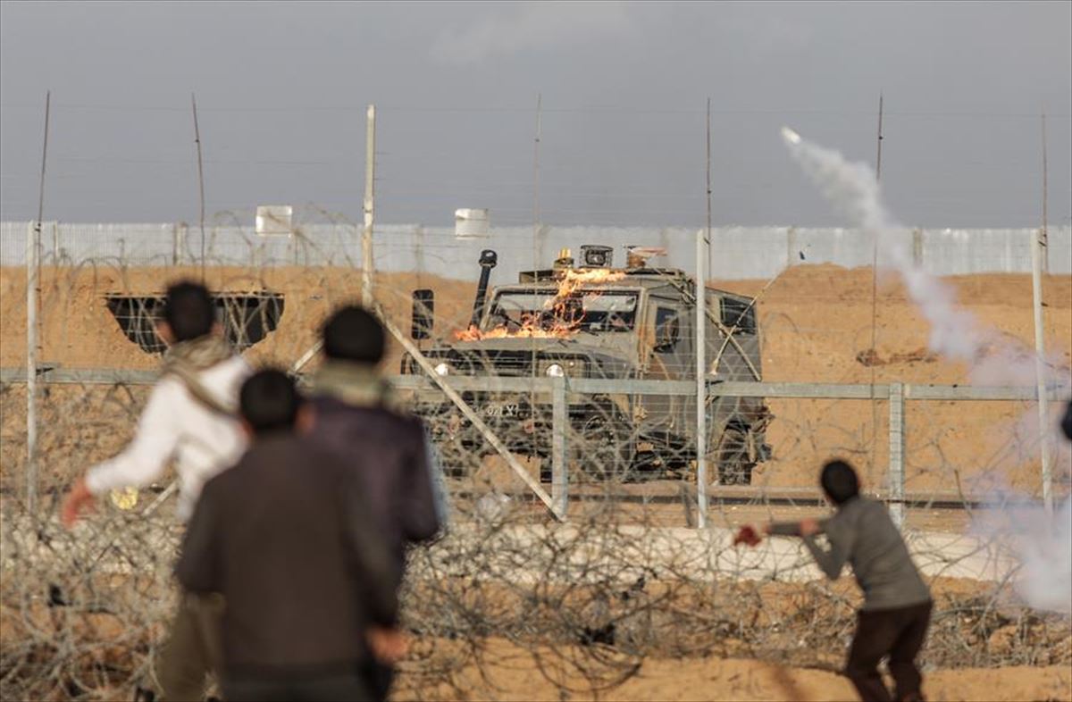 Palestinar zibilek gas negar-eragilearen granadak bueltan soldadu israeldarrei botatzen. EFE. 