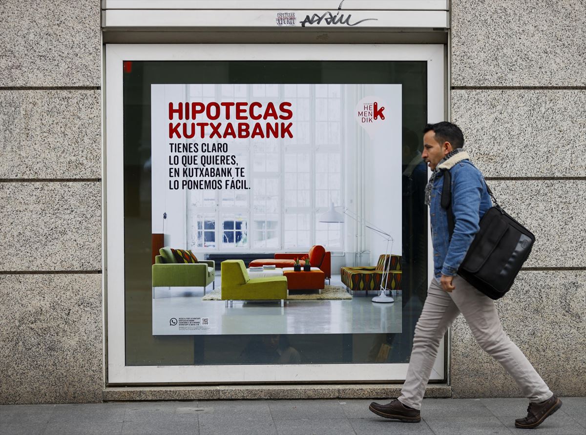 Un hombre pasa por delante de un cartel de Kutxabank. 