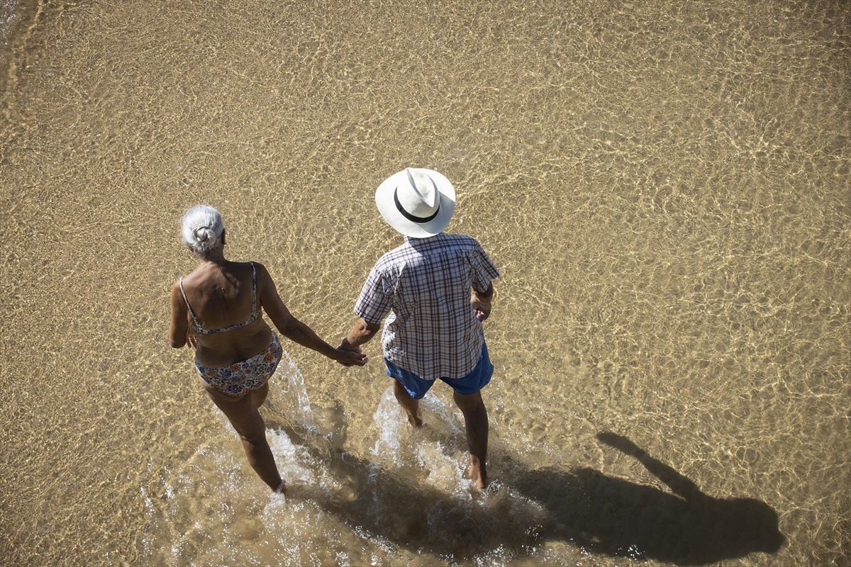 Una pareja pasea por la playa de La Concha. 