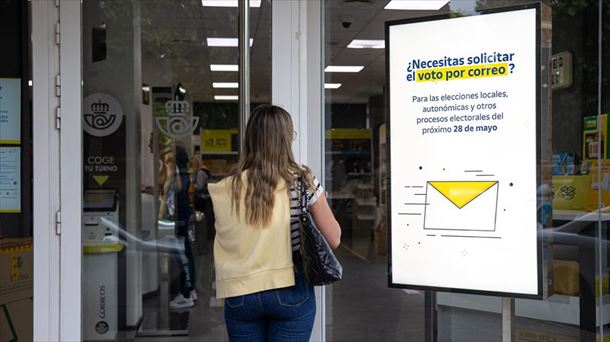 Una oficina de Correos, con el cartel que contempla la posibilidad del voto por correo. Foto: EFE