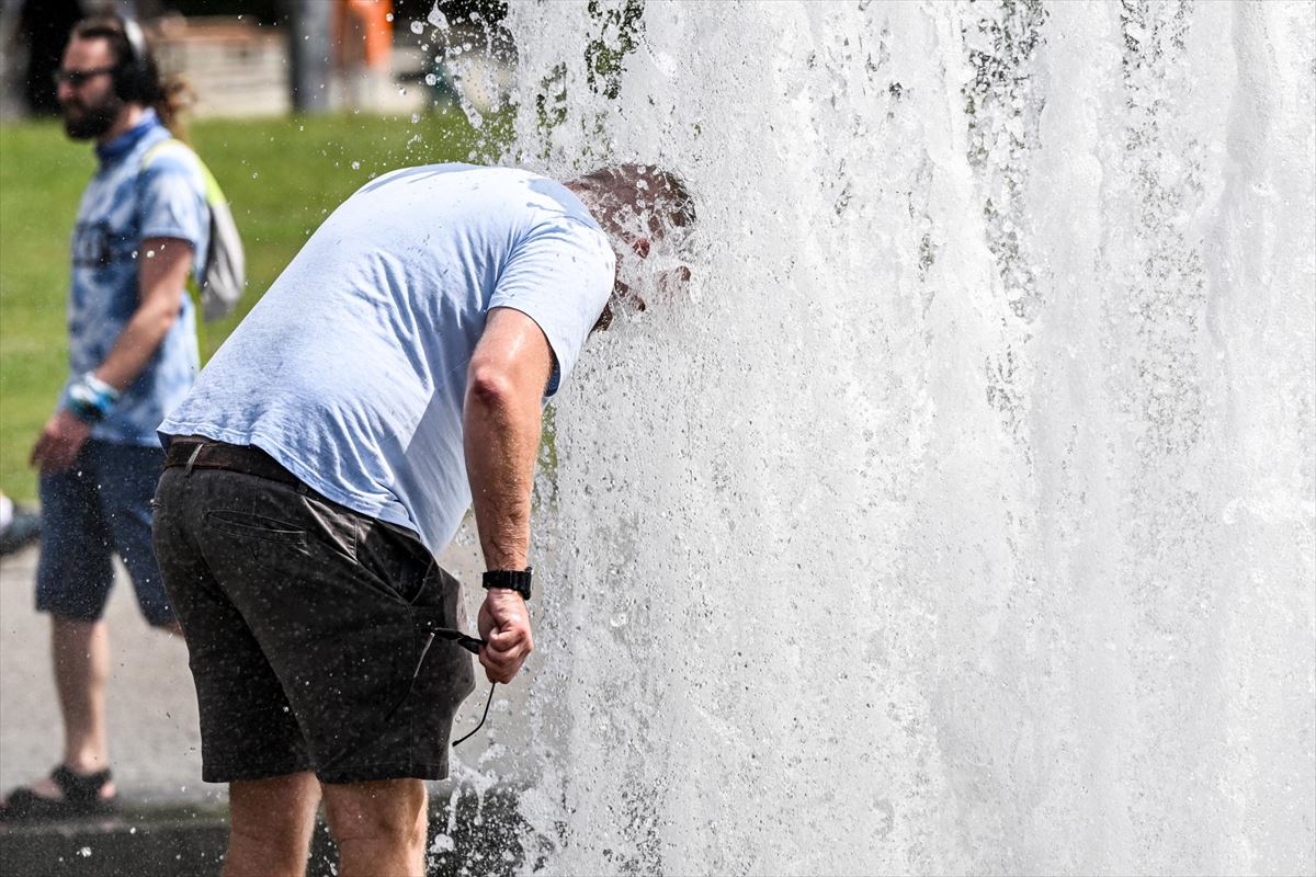 Un hombre se refresca en una fuente de agua
