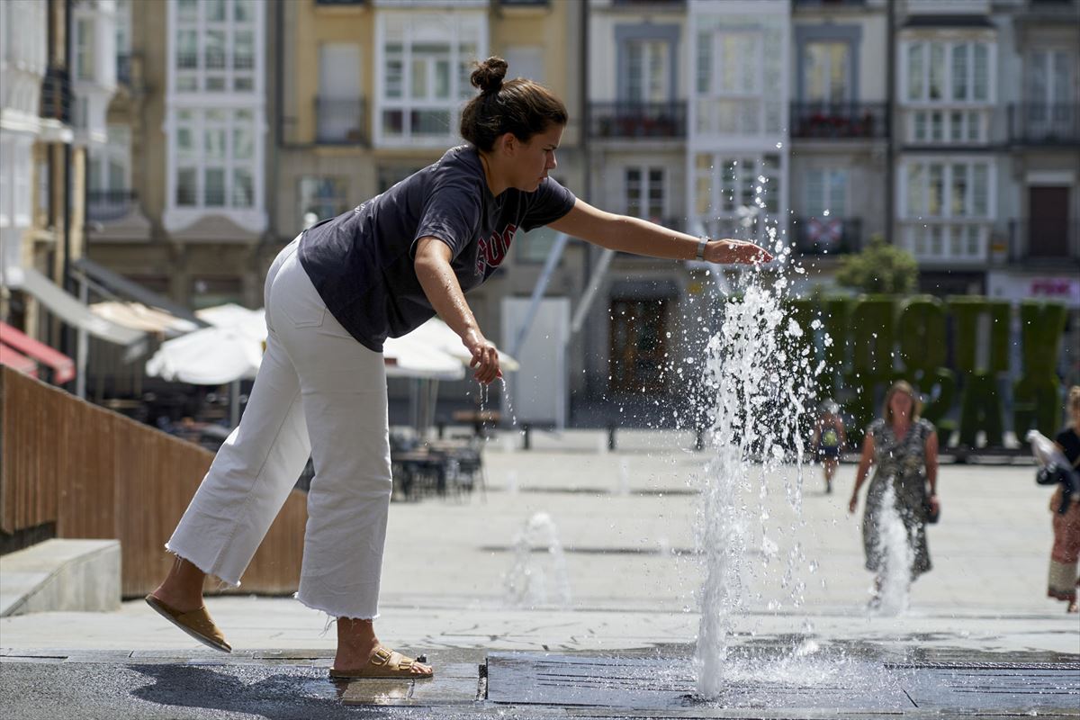 Una mujer se refresca en una fuente de la plaza de la Virgen Blanca de Vitoria. Foto: EFE