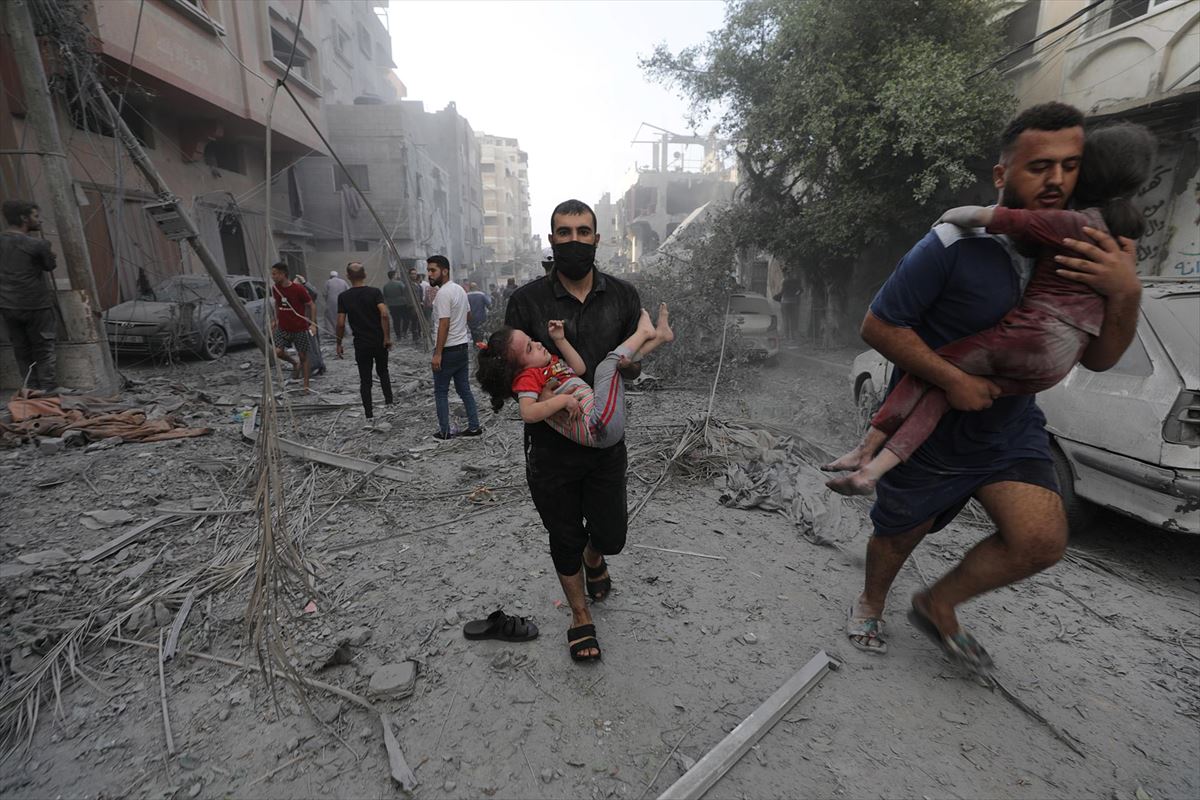 Dos hombres llevan en brazos a dos niños heridos tras los bonbardos en Gaza. Foto: EFE