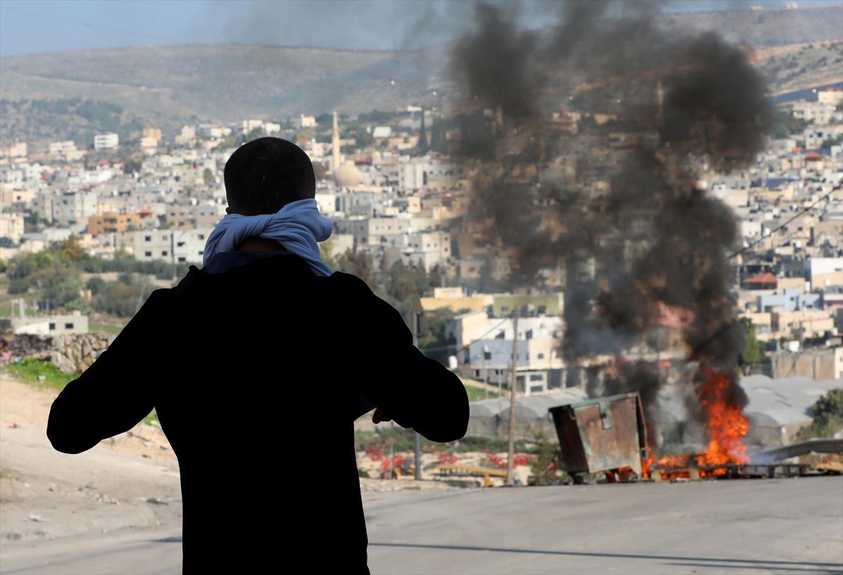 Un palestino observa una barricada en llamas durante una ataque israelí en Cisjordania
