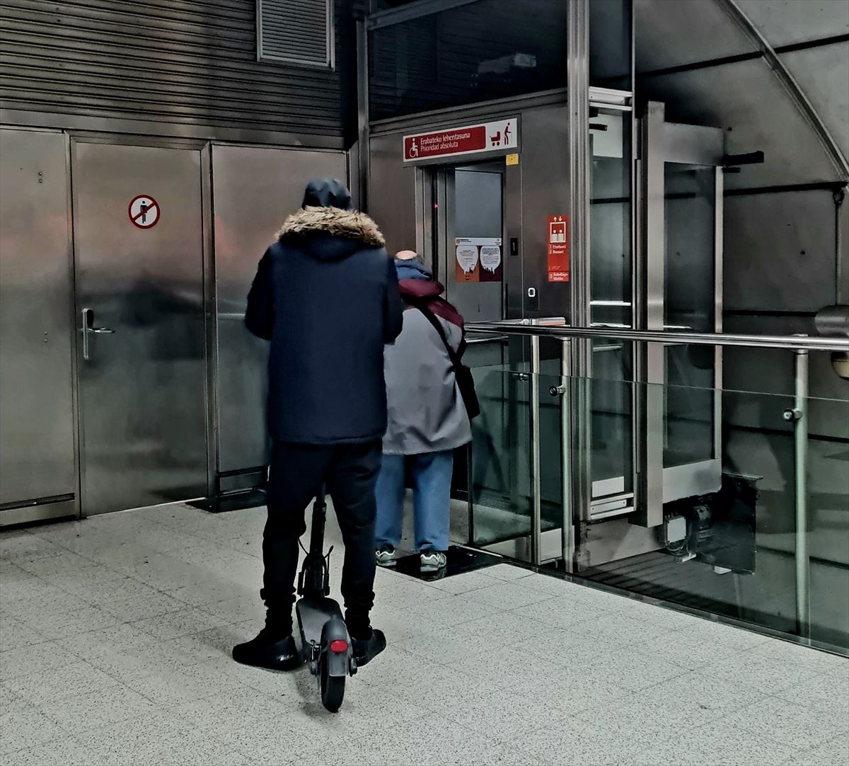 Un usuario de Metro Bilbao con un patinete esperando para entrar en el ascensor.