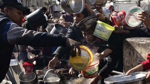 Palestinos desplazados sostienen cazuelas vacías para recibir ayuda al sur de la Franja de Gaza.