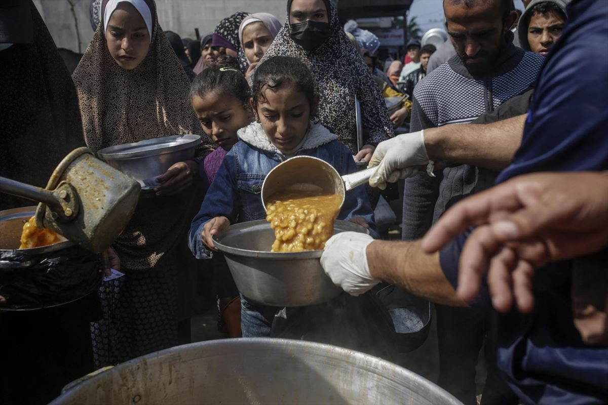 Una niña recibe comida en Deir Al Balah. Foto: EFE