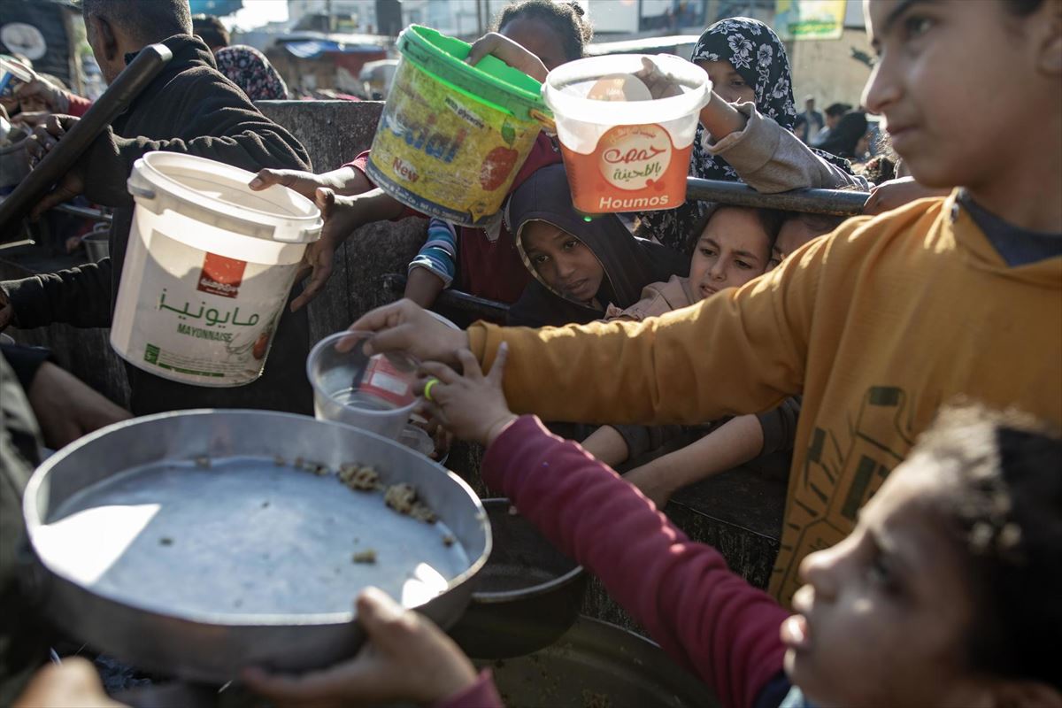 Niños y mayores reciben comida en la Franja de Gaza. Foto: EFE