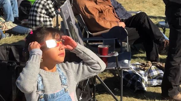 Una niña observa, debidamente protegida, un eclipse de sol. 