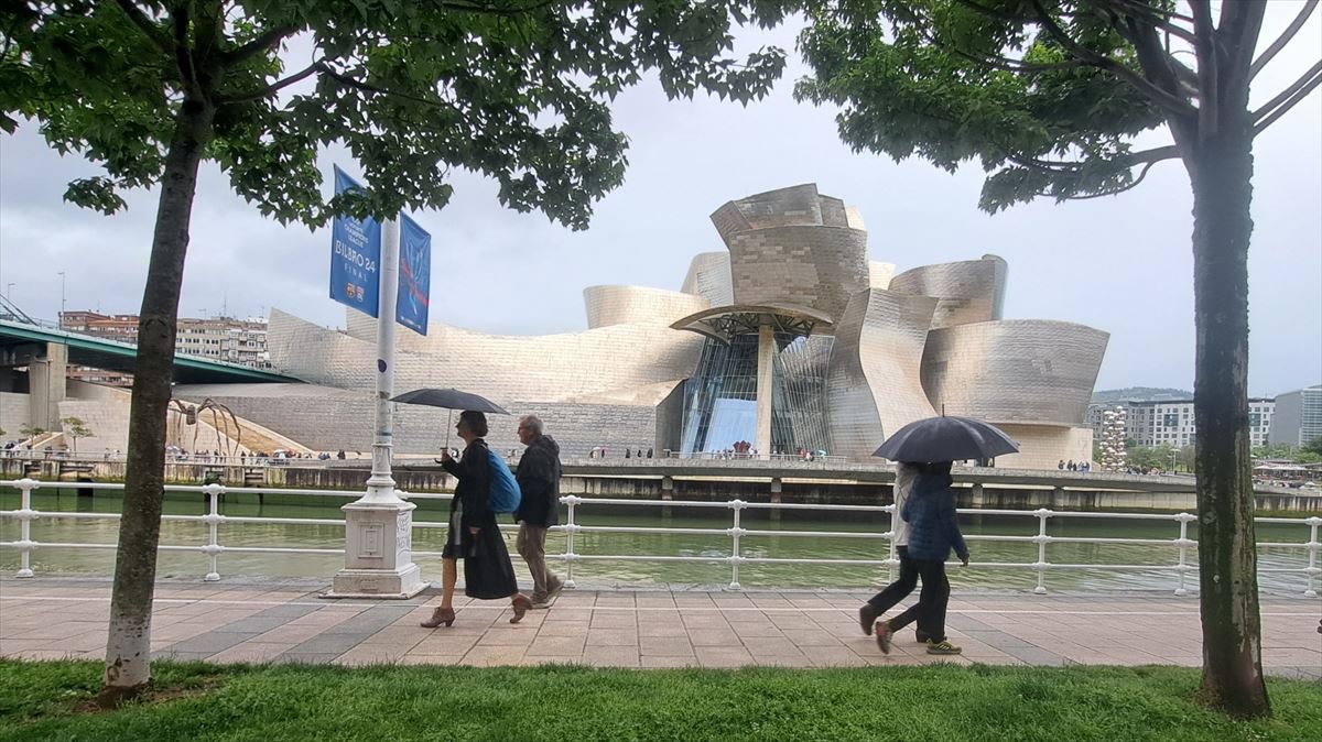 Paseantes con paraguas delante del Guggenheim Bilbao. Foto: Jose Luis Albaizar