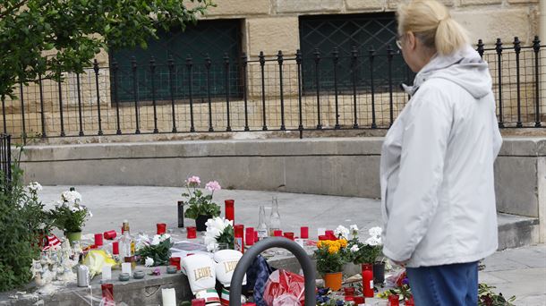 Una mujer observa las flores y los recuerdos en memoria del joven apuñalado. 