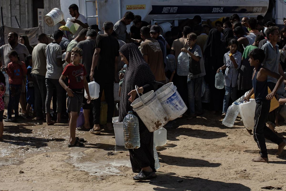 Personas refugiadas hacen cola para lograr agua en Gaza.