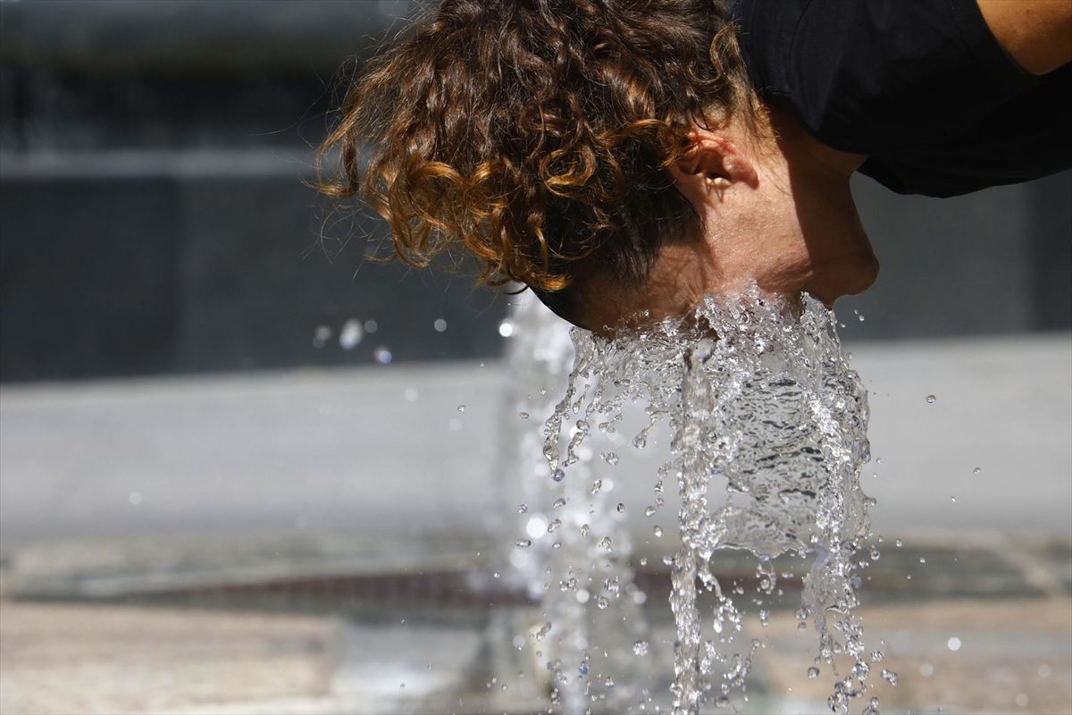 Una mujer se refresca en una fuente. Foto: EFE. 