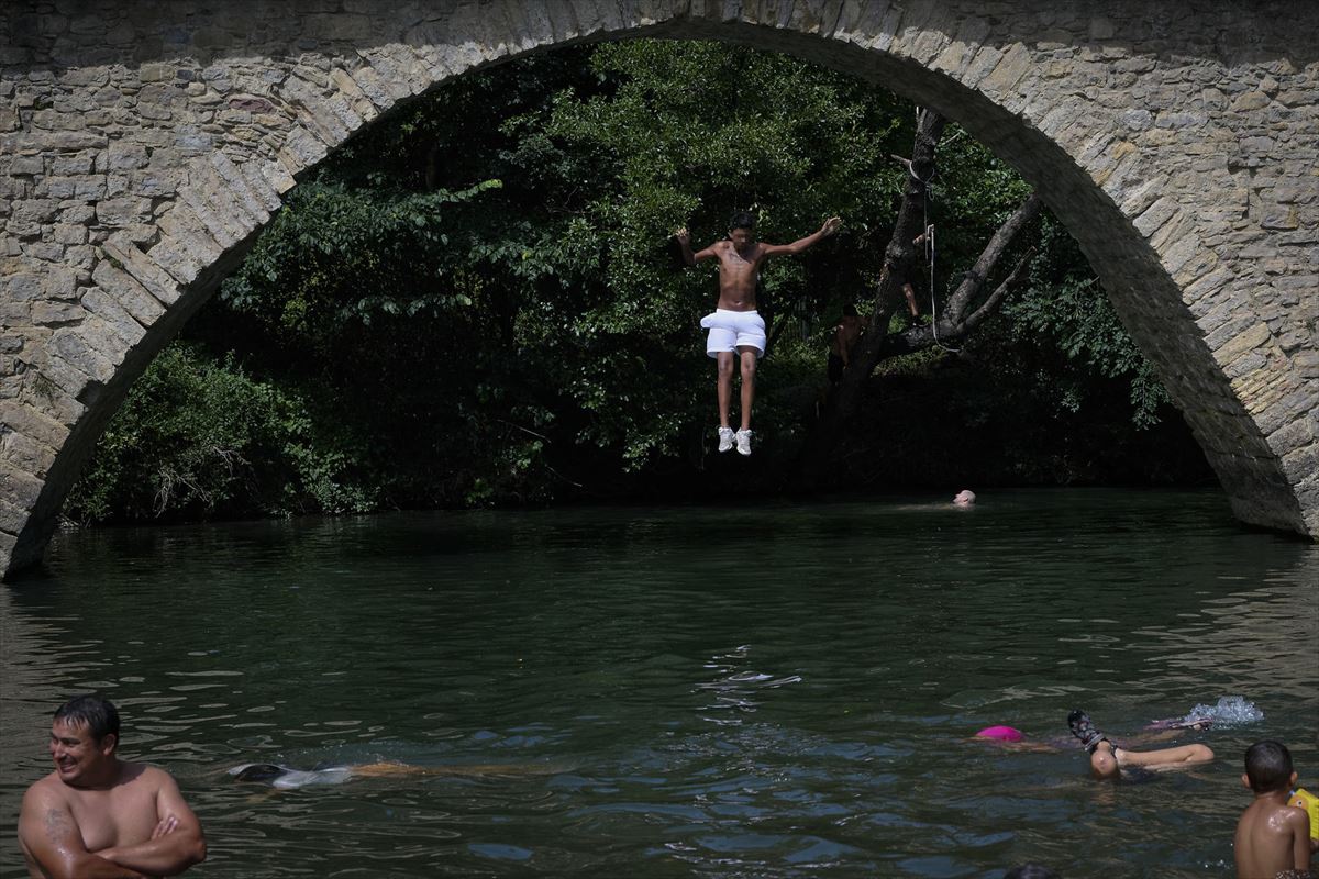 Un joven se lanza al río Arga para refrescarse desde el puente de Irotz. Foto: EFE