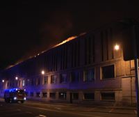 Bomberos tratan de extinguir el incendio en el tejado del edificio de la Policía Municipal de Pamplona