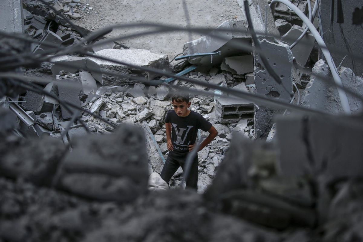 Un ninño busca entre los escombros tras los brutales bombardeos de Israel en Dei Al Balah (Gaza). Foto: EFE