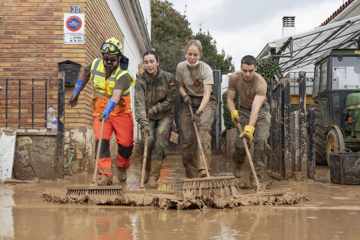 Varias personas limpiando lodo en una zona afectada por la DANA. Foto: EFE