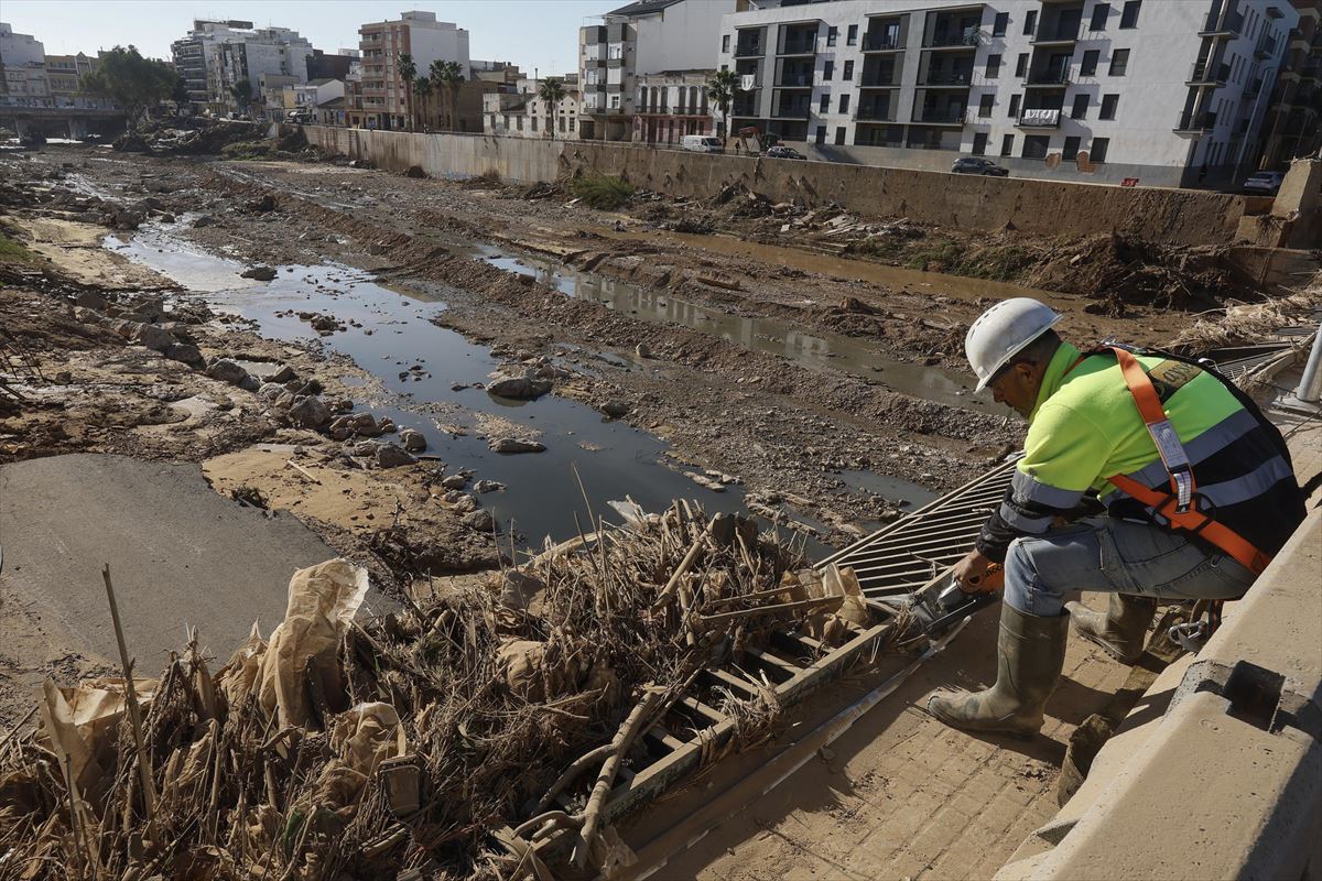 Un trabajador corta con una radial la barandilla metalica de uno de los puentes de Paiporta. Foto: EFE