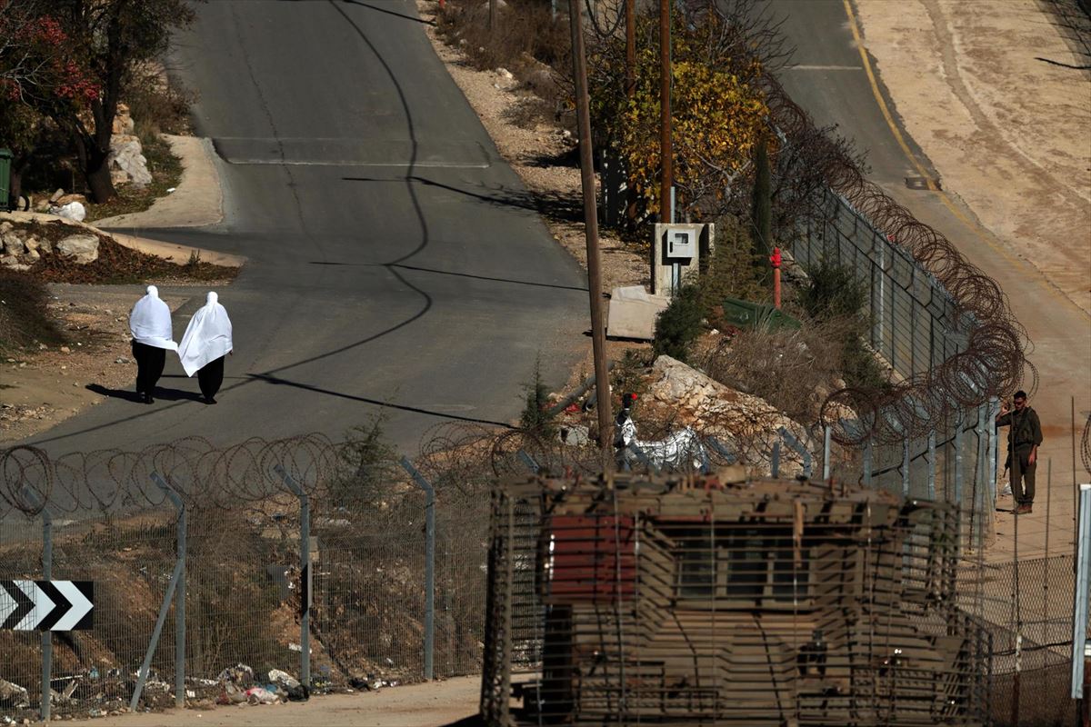 Emakume drusoak soldadu israeldarren ondotik igarotzen, Golango Gainetan. Argazkia: EFE