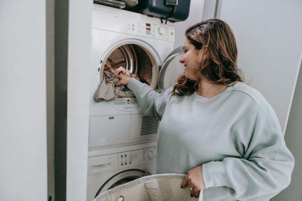 Una mujer mete ropa en la lavadora