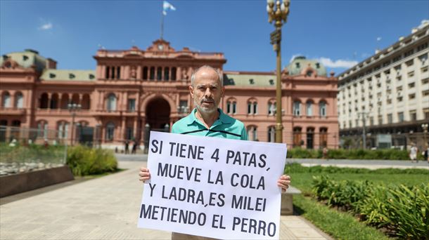 Gizon batek Mileiren aurkako pankarta bati eusten dio Etxe Arrosaren aurrean. Argazkia: EFE