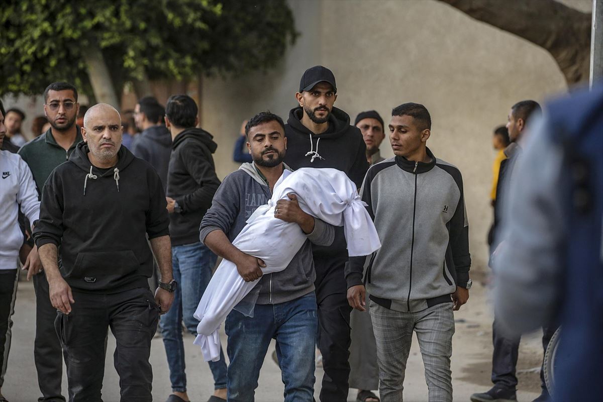 Un palestino porta el cuerpo de uno de los menores asesinados por Israel en la escuela Dar Al-Arqam. Foto: EFE
