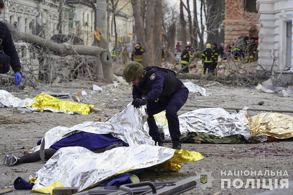 Un policía ucranio rodeado de cadáveres tapados con mantas. Foto: EFE