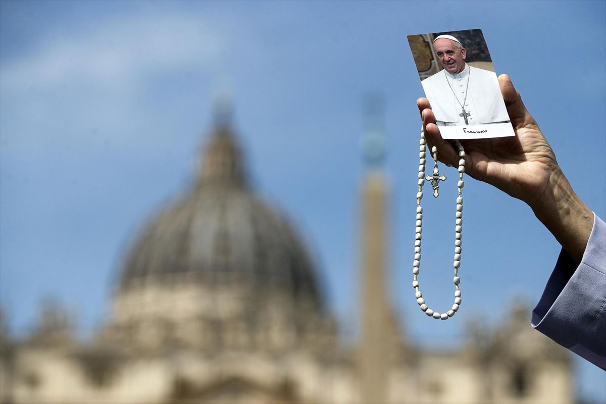 Una mujer sujeta un rosario y una estampa con la imagen del papa Francisco. Foto: EFE