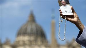 Una mujer sujeta un rosario y una estampa con la imagen del papa Francisco. Foto: EFE